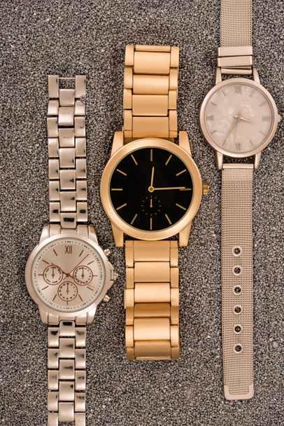 top view of luxury wristwatches lying on golden sand  - 写真・画像