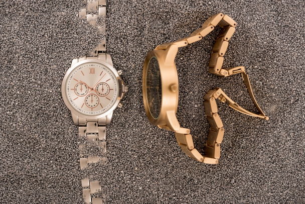 top view of wristwatches lying on golden sand  - Fotó, kép