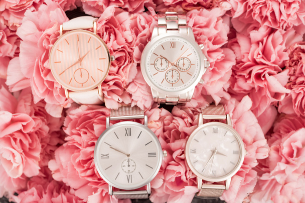 top view of wristwatches lying on blooming pink flowers  - Photo, Image