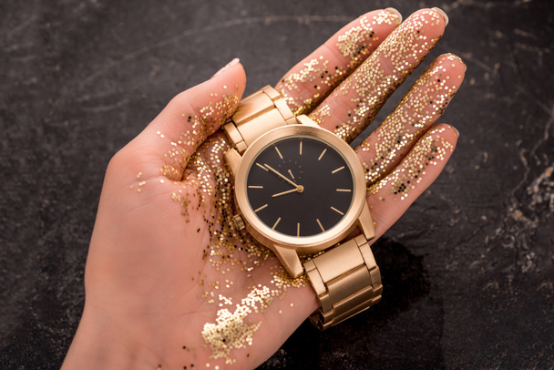 cropped view of golden wristwatch in hand of woman  - Foto, Bild