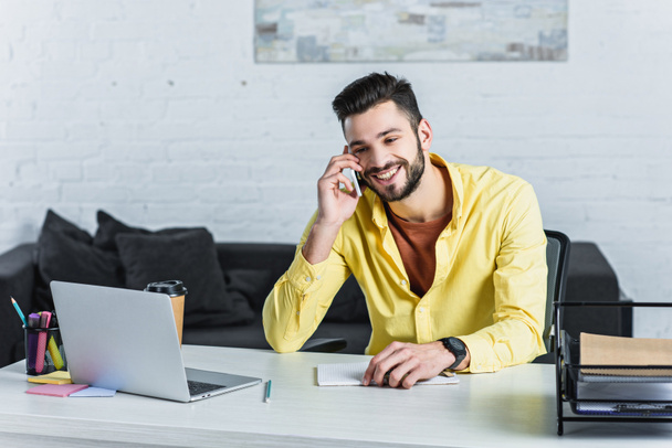 Smiling bearded businessman talking on smartphone at office - Foto, immagini