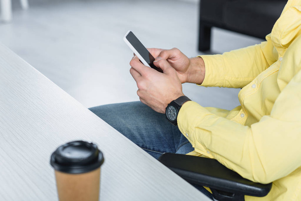 Partial view of man holding smartphone at workplace - Photo, image
