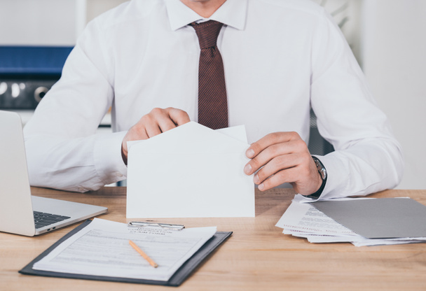 cropped view of businessman opening envelope in office, compensation concept - Photo, Image