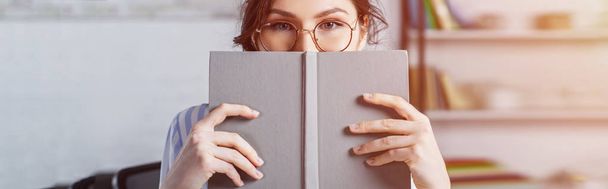 donna in occhiali che copre il viso con il libro
  - Foto, immagini
