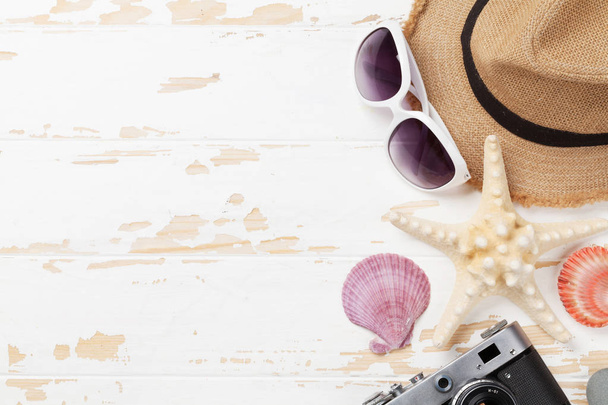 Reise-Hintergrundkonzept mit Kamera, Badehut, Sonnenbrille und Muscheln auf Holztisch. Ansicht von oben mit Kopierraum. flache Lage - Foto, Bild