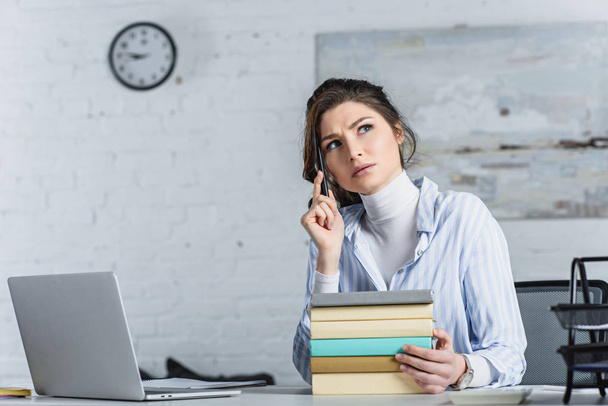 pensive woman sitting near books in modern office  - Фото, изображение