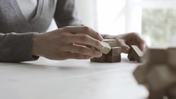 Woman playing with a wooden brain teaser puzzle, she is trying to put pieces together, problem solving concept - Footage, Video