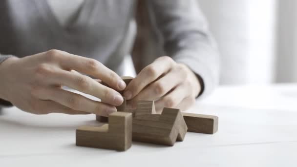 Smart woman playing with a wooden brain teaser puzzle on a desk, she finds a solution and solves it - Felvétel, videó
