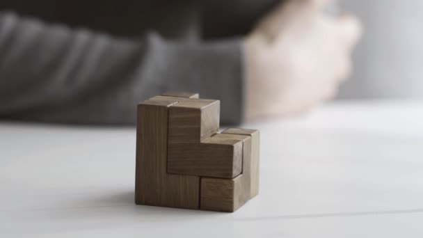 Smart woman playing with a wooden brain teaser puzzle on a desk, she finds a solution and solves it - Imágenes, Vídeo