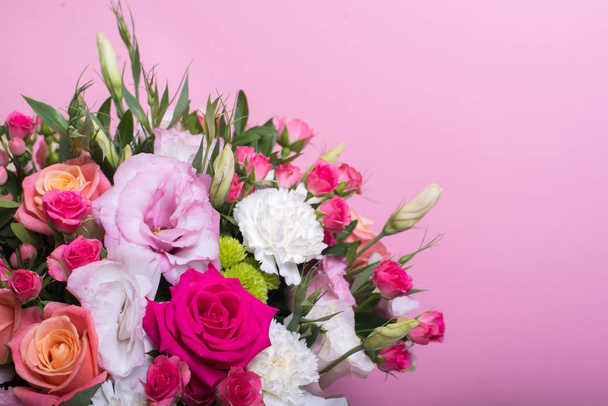 beautiful floral arrangement in the box, pink and yellow rose, pink eustoma, green and pink chrysanthemum, white carnation, pink dahlia on pink background with space for text. - Фото, зображення
