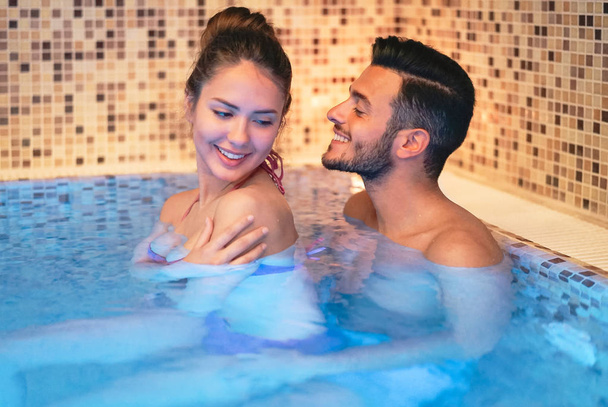 Jovem casal feliz fazendo um dia de centro de spa piscina - Amantes românticos tendo um momento terno em férias no hotel de bem-estar resort - Relacionamento, recreação, relaxamento e conceito de amor
 - Foto, Imagem