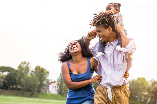 Happy African family enjoy together in public park - Mère, père et fille s'amusent pendant un week-end ensoleillé en plein air - concept de bonheur, d'amour et de parentalité
 - Photo, image