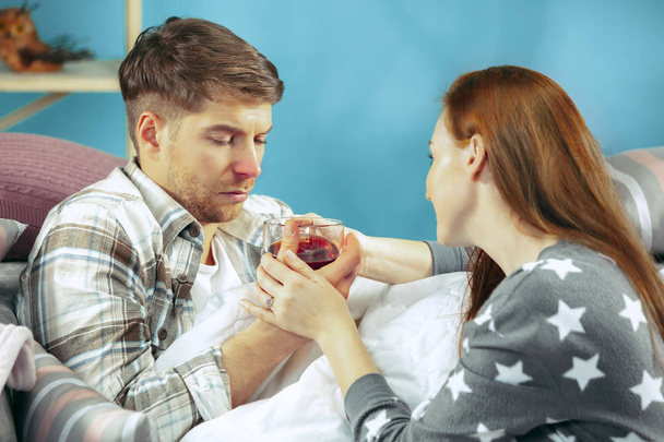 Sick man with fever lying in bed having temperature girl take care for him - Photo, Image