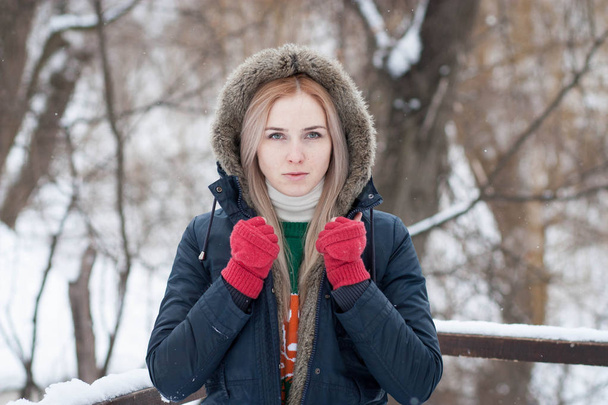 Muotokuva kaunis ilmeikäs nuori tyttö pitkät vaaleat hiukset lämpimässä takissa talvipuistossa
 - Valokuva, kuva