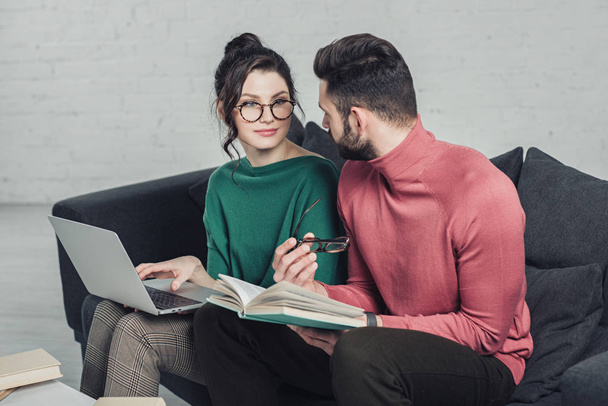  man looking at cheerful woman in glasses sitting with laptop - Foto, Imagen