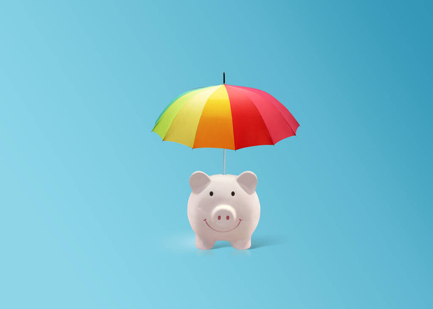 pink piggy ceramic bank with colorful rainbow umbrella, safe insurance - Photo, Image