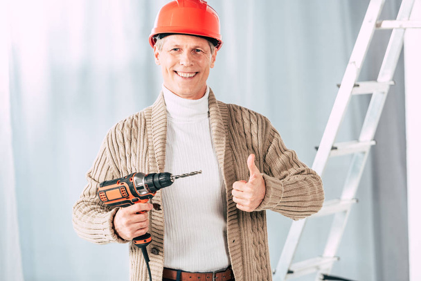 middle aged man in beige cardigan holding screwdriver at home - Foto, afbeelding