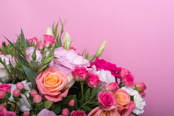 beautiful floral arrangement in the box, pink and yellow rose, pink eustoma, green and pink chrysanthemum, white carnation, pink dahlia on pink background with space for text. - Photo, image