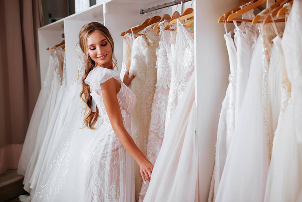 Back view of a young woman in wedding dress looking at bridal gowns - Valokuva, kuva