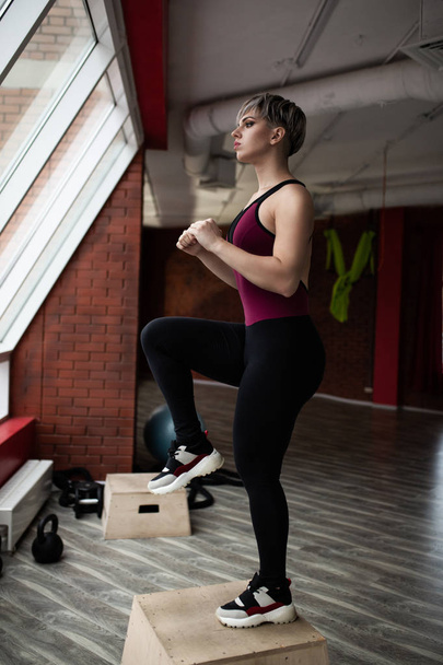 Женщина со ступенчатой платформой делает перекрестные упражнения. Снимок студии
 - Фото, изображение