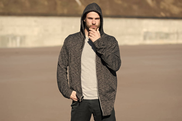 Bearded man wear casual sweatshirt outdoor. Guy touch beard on sunny day. Fashion macho in stylish sportswear. Lifestyle for active and healthy man. Skincare and barber salon - Foto, afbeelding