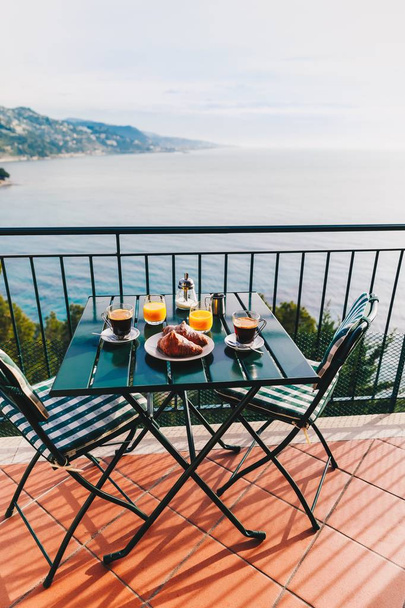 Delicious breakfast with coffee, pastry, and orange juice served on the balcony with sea view in Italy. - Photo, image