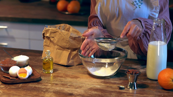 câmera lenta do cozinheiro feminino peneirando farinha de saco de papel em tigela de vidro
 - Filmagem, Vídeo