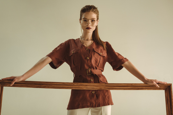 atraktivní model představuje s velkým dřevěným rámem izolované na béžové - Fotografie, Obrázek