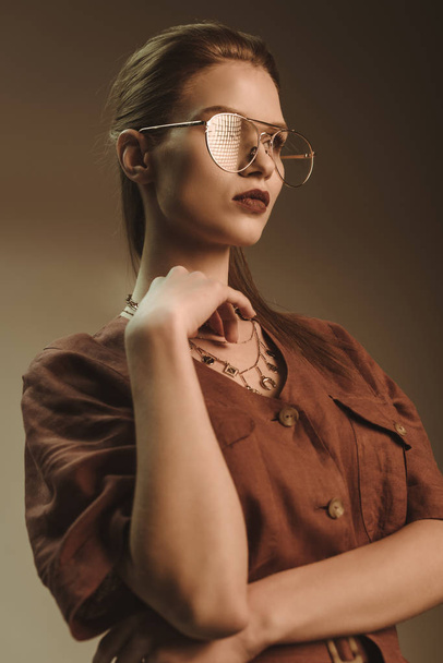 attractive stylish woman posing in glasses isolated on brown - Photo, Image