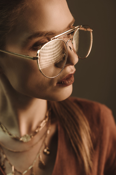 attraktive modische Frau posiert in Brille isoliert auf braun - Foto, Bild