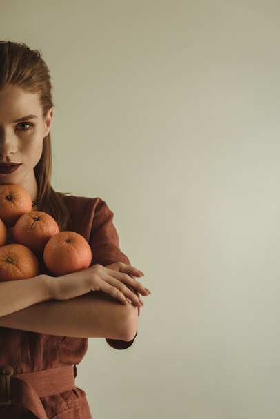 half view of beautiful fashionable girl holding fresh oranges isolated on beige - Valokuva, kuva