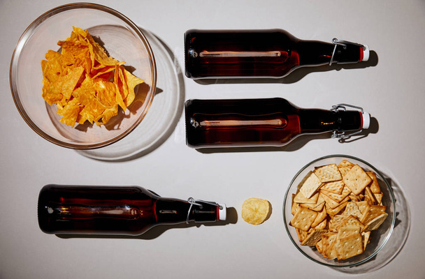 felülnézet üveg sör közelében ízletes harapnivalókat, fehér háttér - Fotó, kép