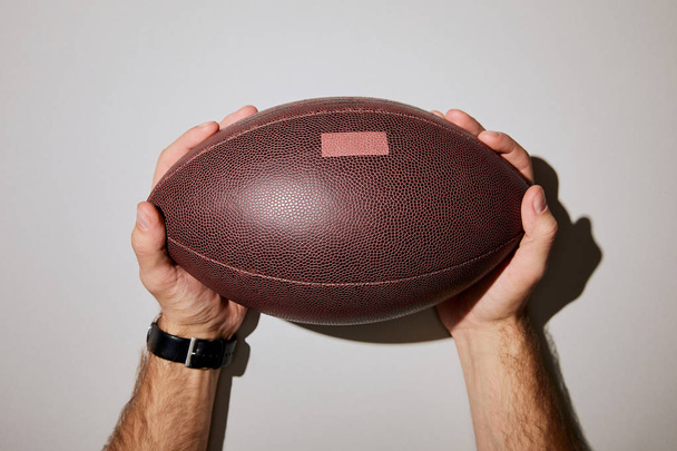 levágott képe ember barna labda tartja kezében a fehér háttér - Fotó, kép