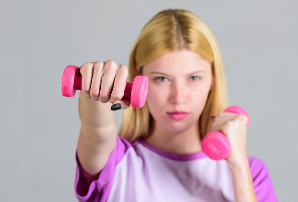 Girl hold dumbbells. Biceps exercises for female. Fitness instructor. Healthy lifestyle concept. Woman fitness coach exercising with dumbbells. Easy exercises with dumbbells. Workout with dumbbells - Foto, afbeelding