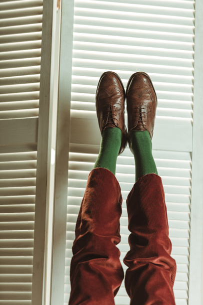 vista cortada de pernas em sapatos de couro elegantes perto da tela dobrável
 - Foto, Imagem
