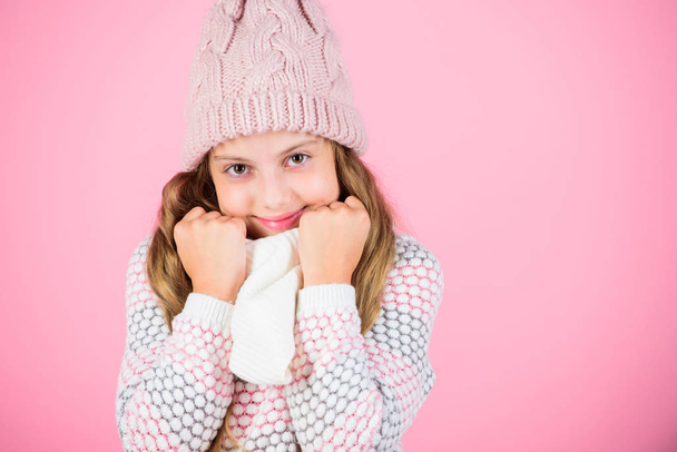Winter fashion warm clothes concept. Warm accessories that will keep you cozy winter. Child long hair warm woolen hat enjoy warm and softness. Kid girl wear knitted warm hat relaxing pink background - Fotografie, Obrázek