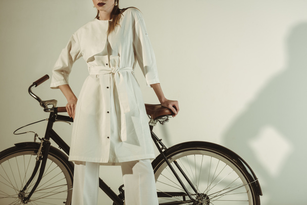 cropped view of fashionable girl in white outfit posing on bicycle - Foto, immagini