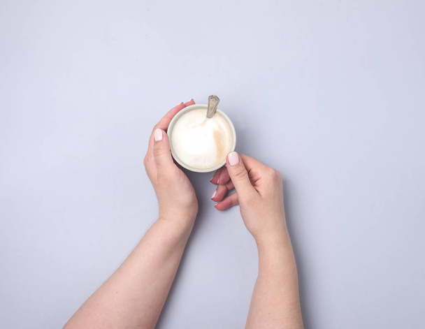 weibliche Hand hält Tasse Kaffee auf blauem Hintergrund flach lag Draufsicht Kopie Raum Cappucino - Foto, Bild