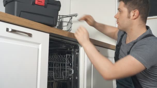 професійний майстер в комбінезоні ремонт побутової посудомийної машини на кухні
. - Кадри, відео