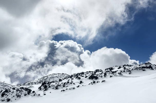 Curly clouds showing behind volcano ridge - Фото, зображення