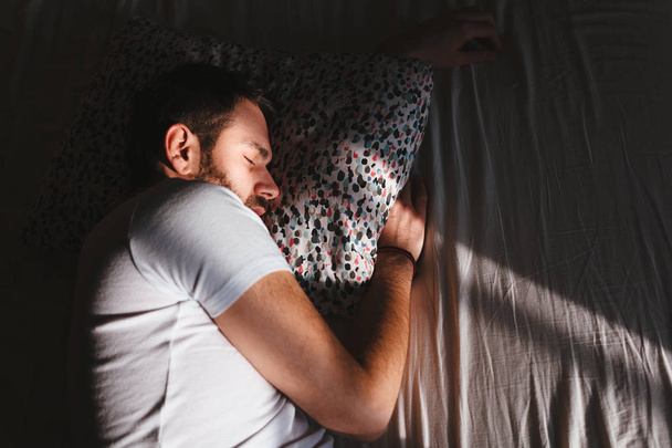 Νεαρός άνδρας στον ύπνο στο κρεβάτι το πρωί - Φωτογραφία, εικόνα