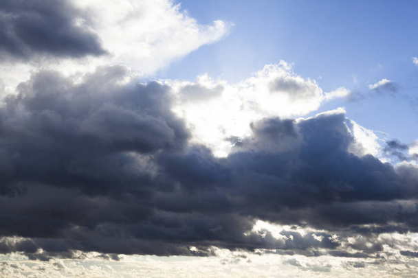 Bulutlar bulutların arkasından ışıldayan güneş ışınlarıyla kaplı. - Fotoğraf, Görsel