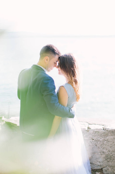 Beautiful young couple embracing and walking in the garden of the Scaliger Castle on the background of Garda Lake. Sirmione, Italy - 写真・画像