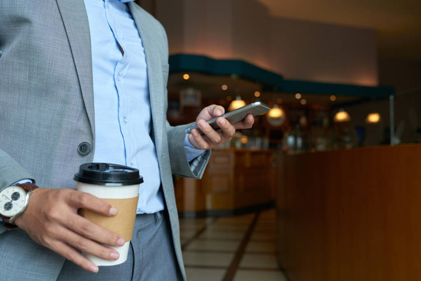 İş adamı elinde fincan eve servis kahve ve smartphone ile - Fotoğraf, Görsel