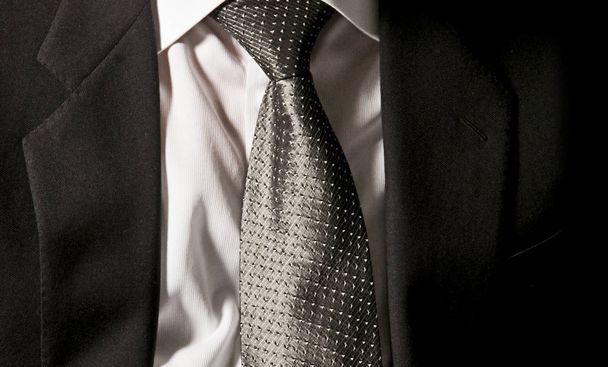 La corbata del jefe. El hombre de negocios lleva su chaqueta gris oscuro en la camisa blanca con una elegante corbata gris
 - Foto, Imagen
