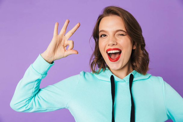 Image of an excited beautiful young woman posing isolated over purple background wall showing okay gesture. - Zdjęcie, obraz