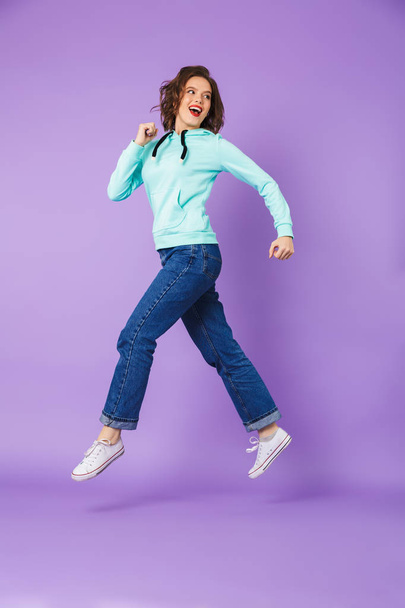 Image of an excited beautiful young woman isolated over purple background wall running. - Foto, immagini