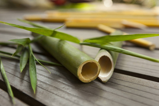 Bâtons ronds de bambou avec des feuilles sur fond en bois. Matière première écologique
. - Photo, image