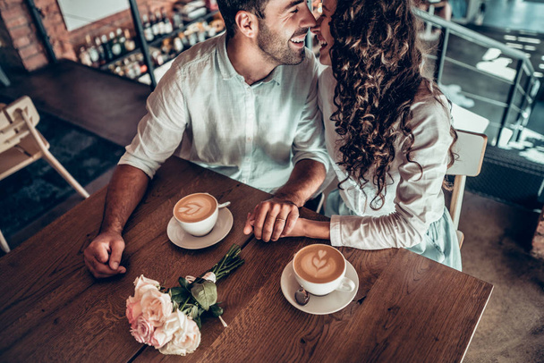 Sentimientos sinceros. Una pareja enamorada se está divirtiendo sentada en un café y bebiendo café
. - Foto, Imagen