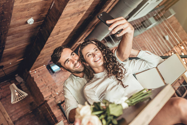 Beautiful couple making selfie on new smartphone. Couple in love spends time in cafe. - Photo, Image